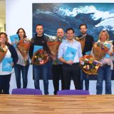 Een groep mensen poseert met bloemen en certificaten.